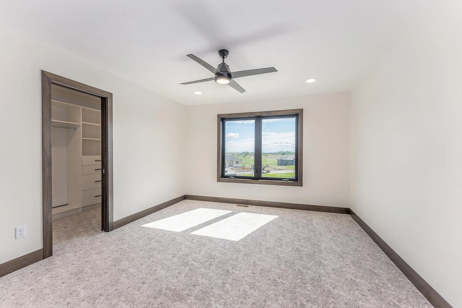 An empty bedroom with a ceiling fan and a window.