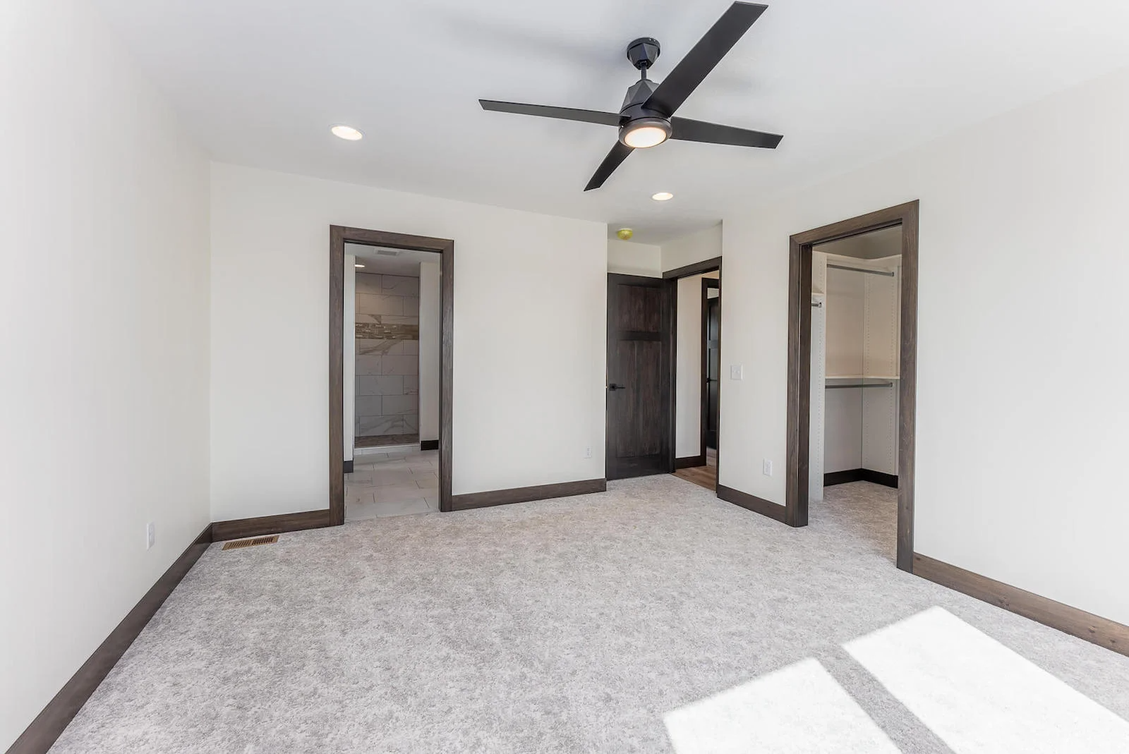 A bedroom with a ceiling fan and a carpeted floor.