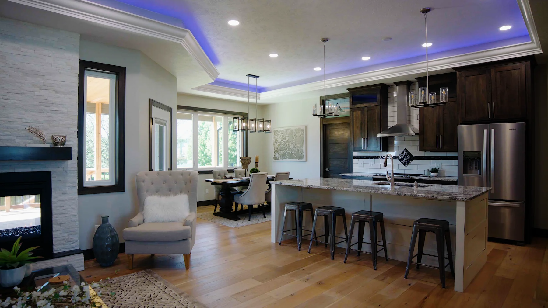 A living room filled with furniture and a kitchen with a purple ceiling.