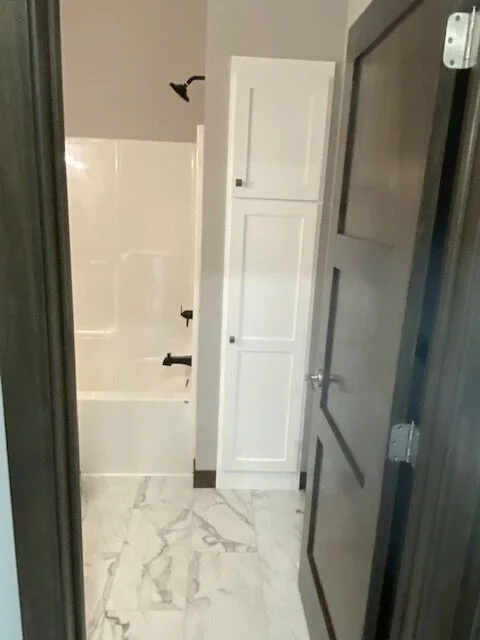 A bathroom with a bathtub , shower and cabinets