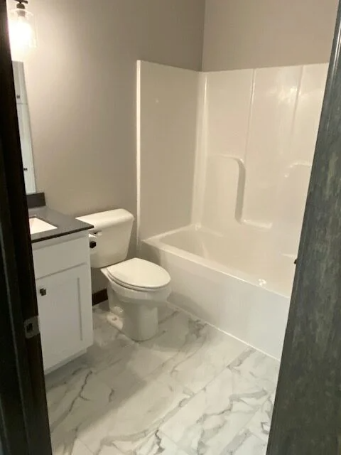 A bathroom with a toilet , sink , and bathtub.