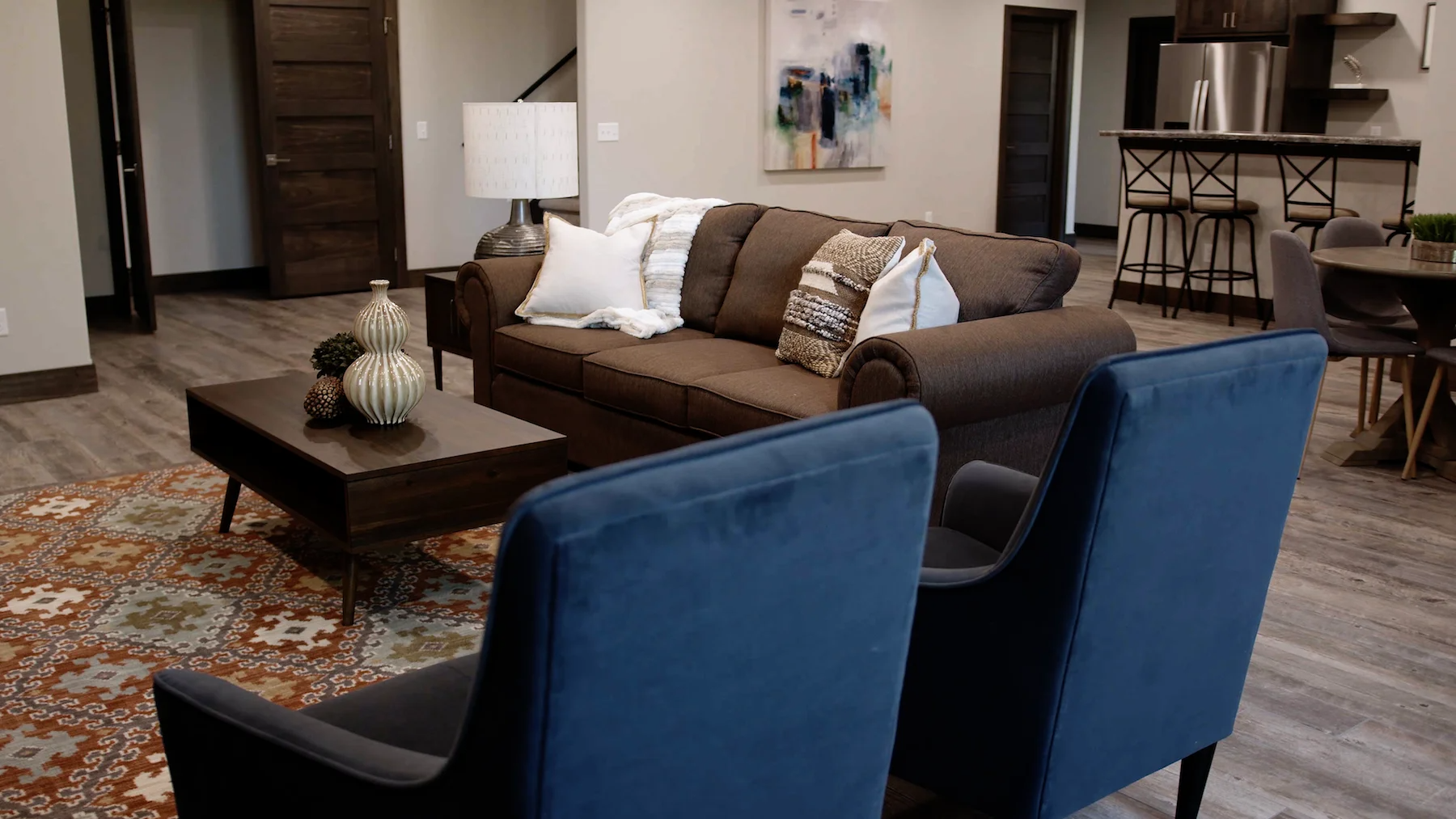 A living room with a couch , two chairs , a coffee table and a rug.