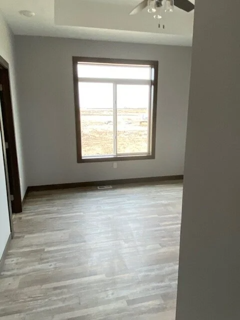 An empty room with a window and a ceiling fan.