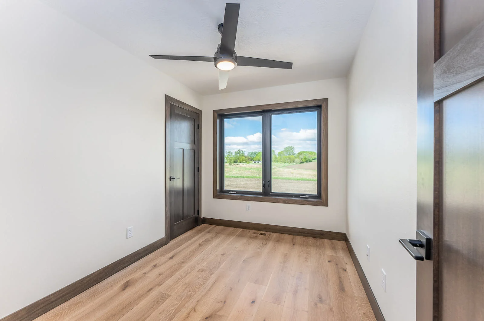 An empty bedroom with hardwood floors and a ceiling fan.