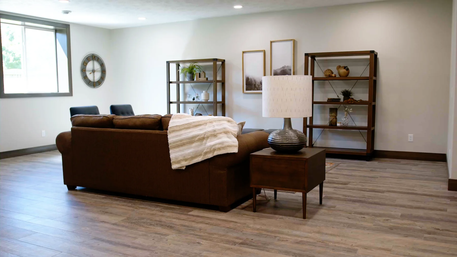 A living room with a couch , table , lamp and shelves.