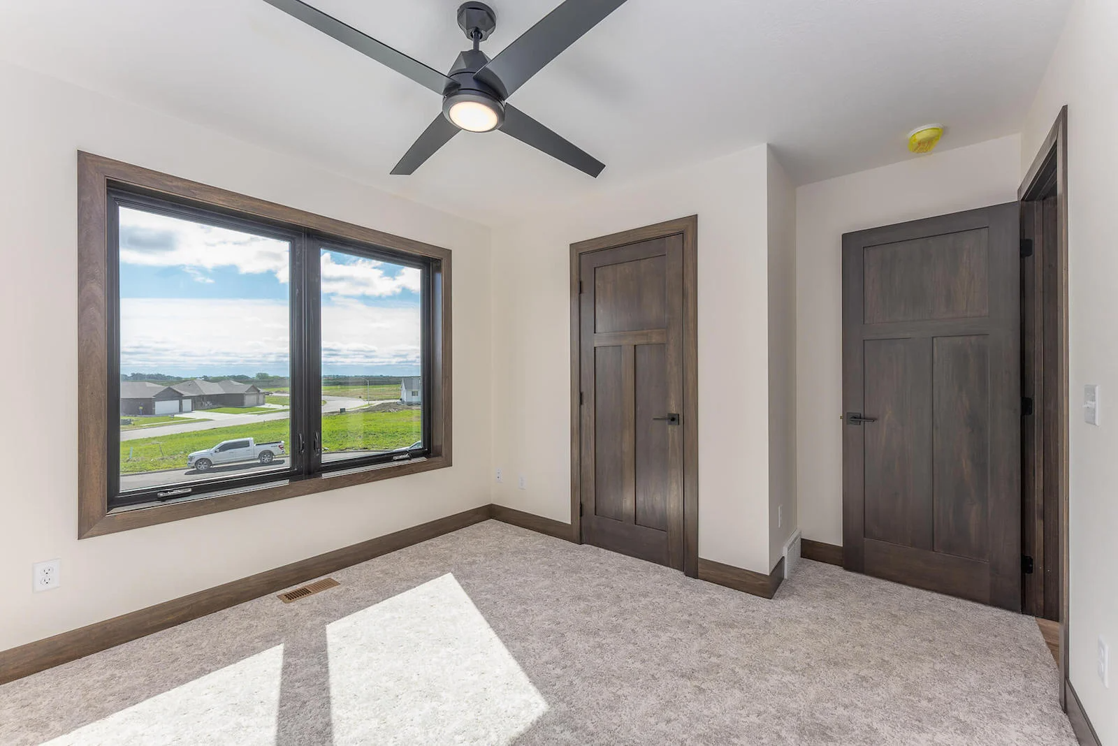 A bedroom with two windows and a ceiling fan.
