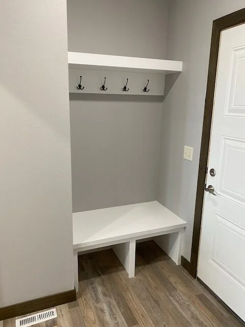 A hallway with a bench and hooks on the wall.