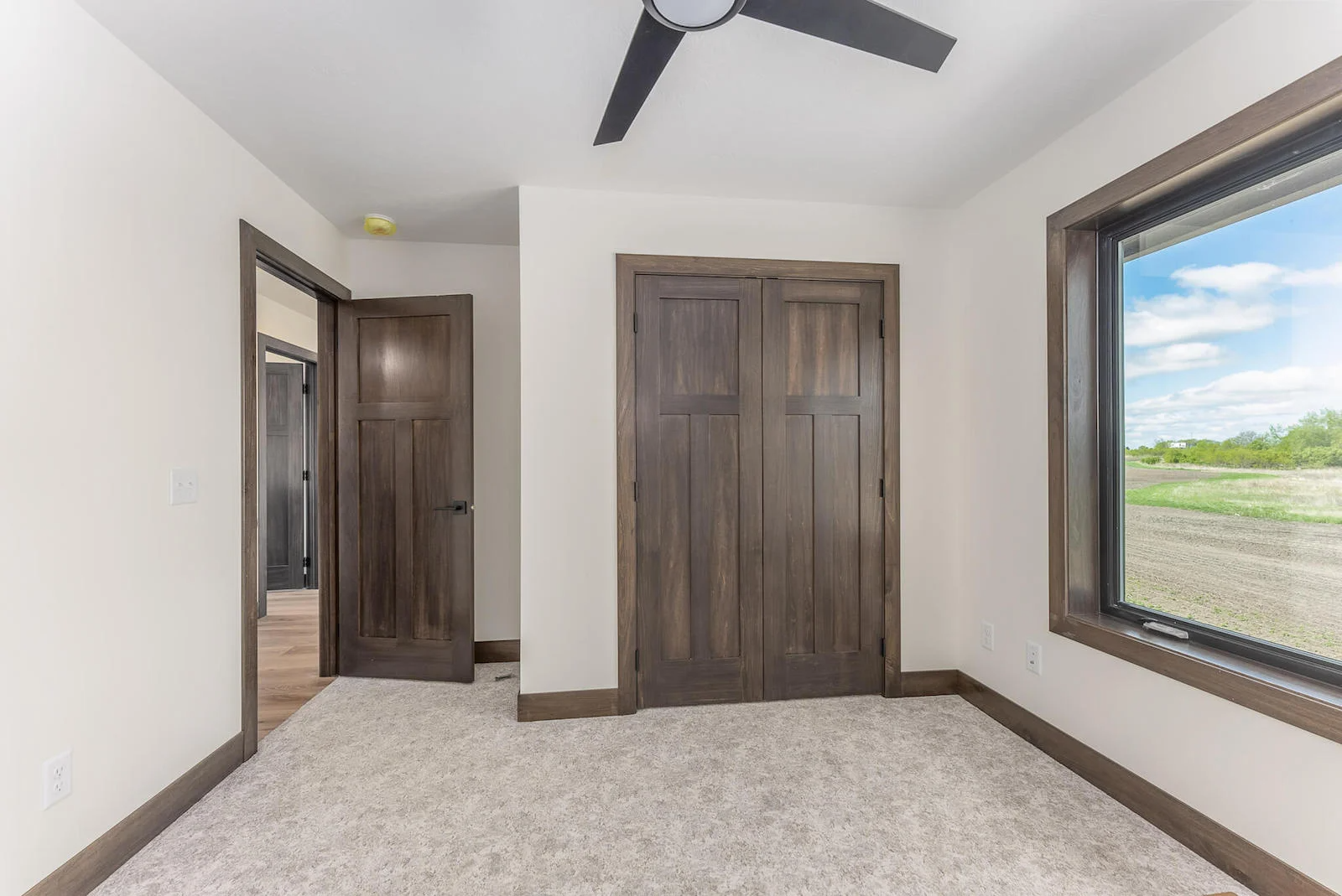 An empty bedroom with a ceiling fan and two windows.