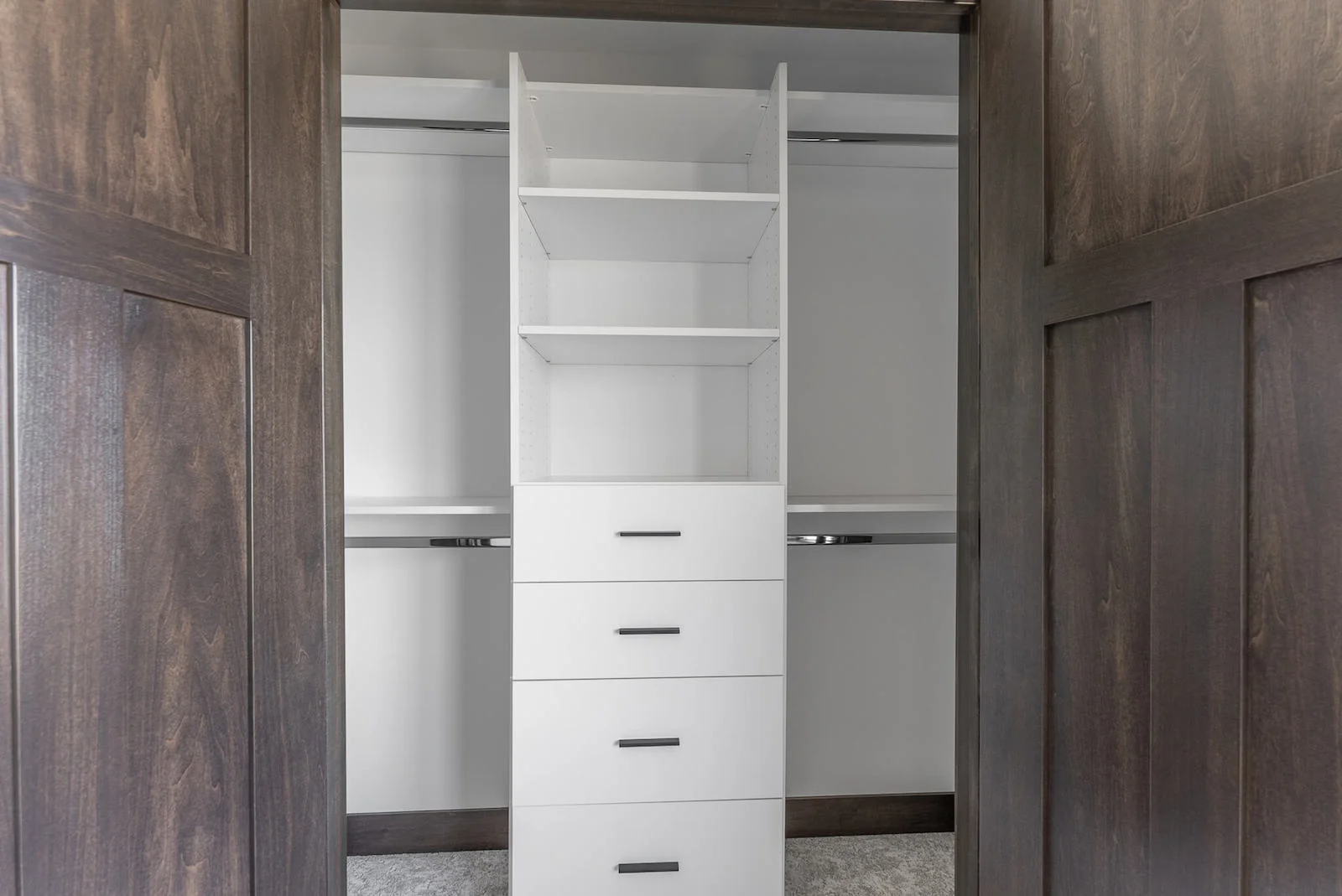 A walk in closet with wooden doors and white shelves and drawers.