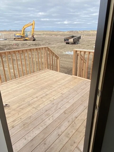 A wooden deck with a yellow excavator in the background.
