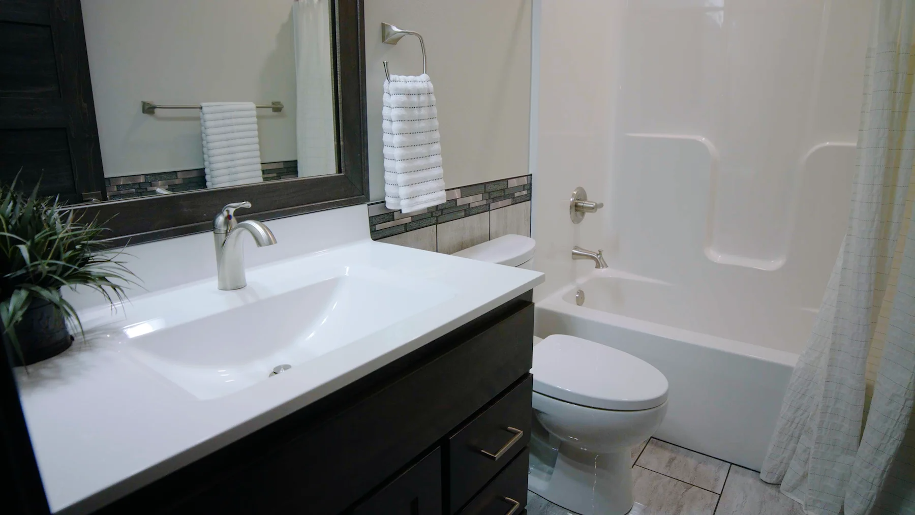 A bathroom with a sink , toilet , tub and mirror.