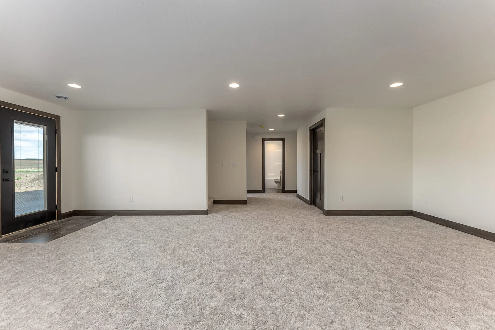 An empty basement with a carpeted floor and white walls.
