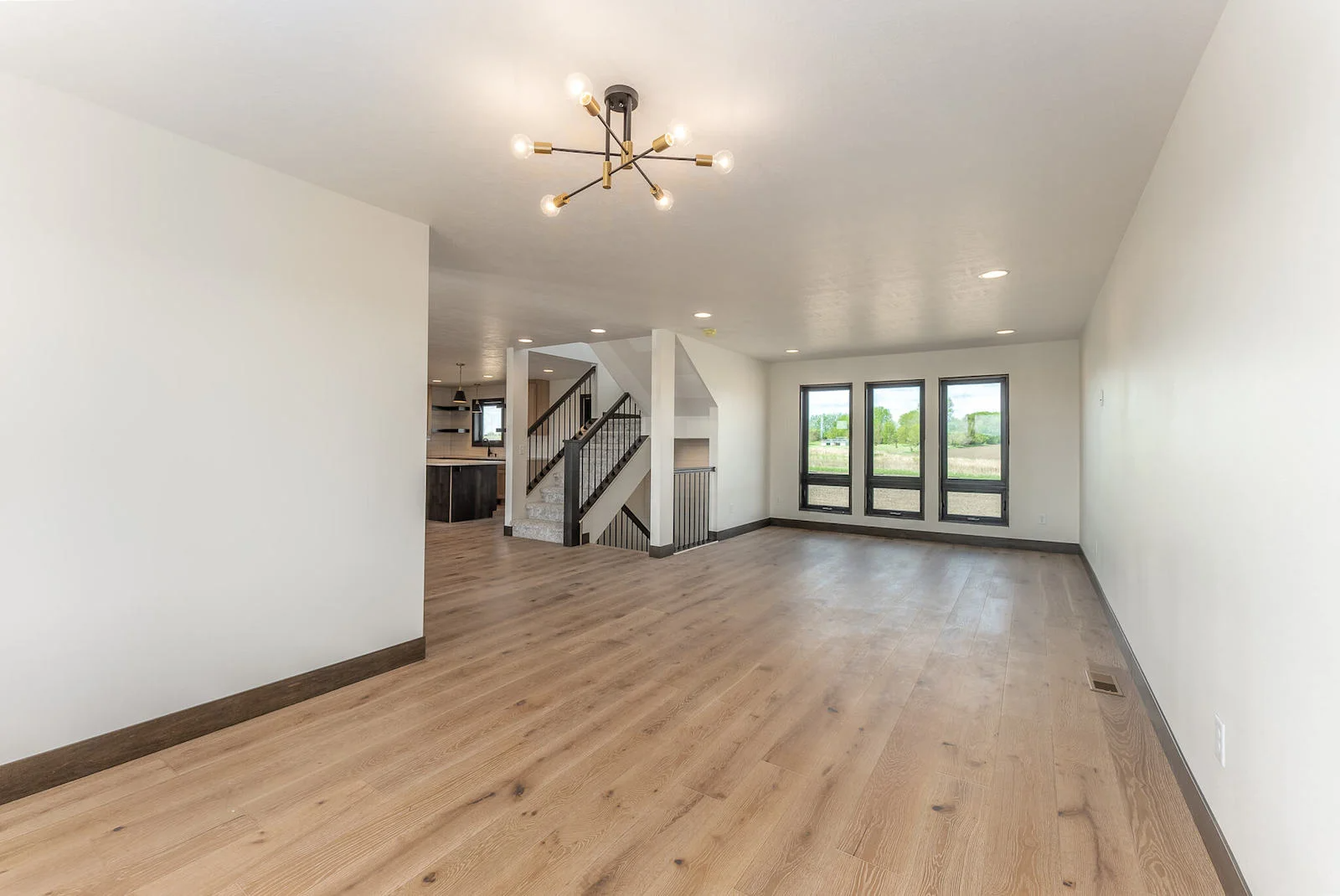 An empty living room with hardwood floors and white walls.