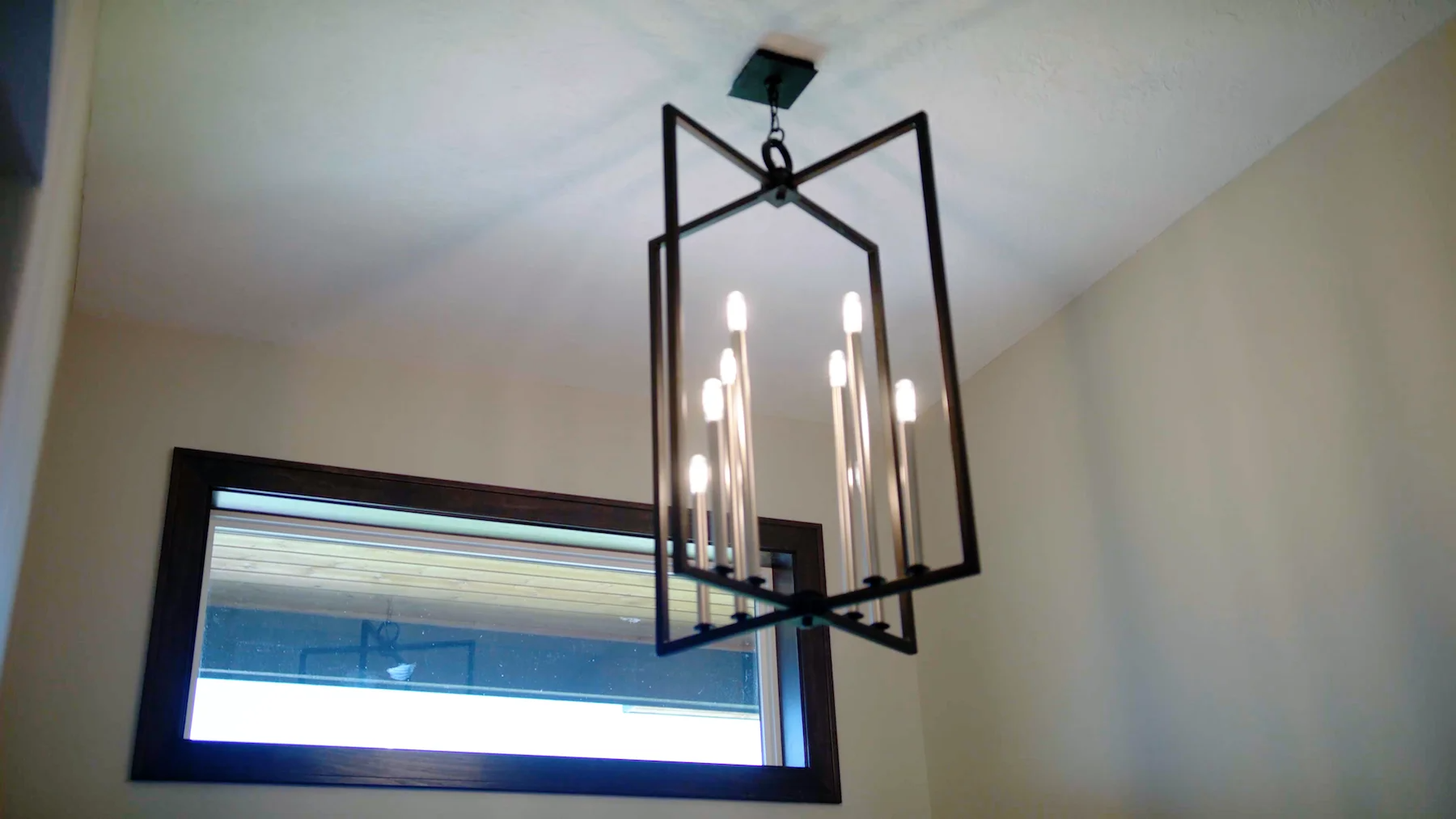 A chandelier is hanging from the ceiling in a room next to a window.