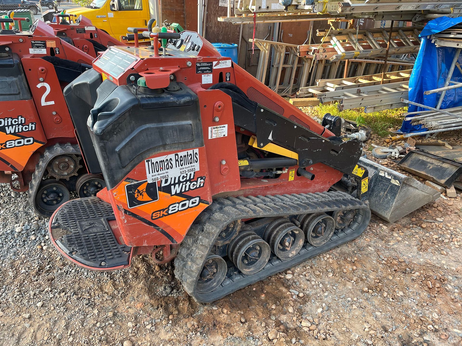 A red and black tractor is parked on a gravel road