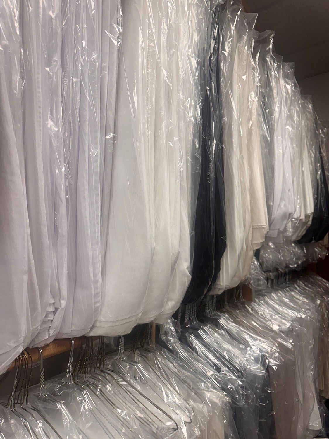 A row of white shirts hanging on plastic hangers in a closet