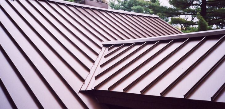 Two overlapping brown metal roof sections with diagonal seams and a ridge in the foreground