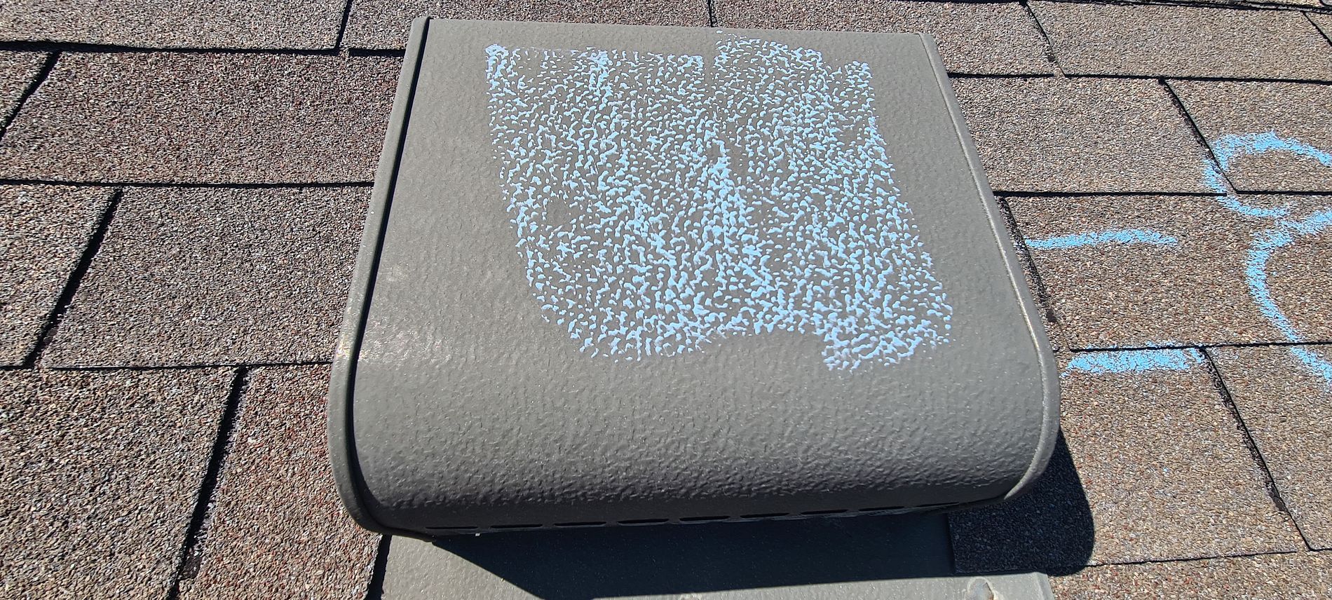 Gray rooftop vent cap with worn white paint on shingle roof