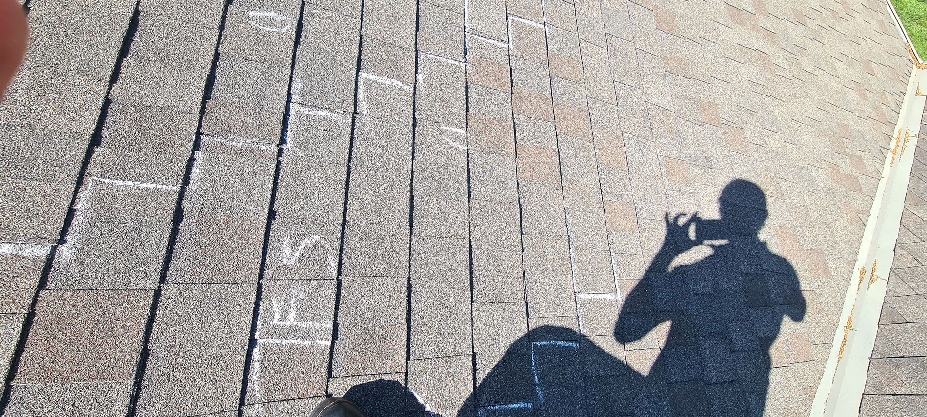 Shadow of a person on a sunlit brick walkway with long diagonal paving lines