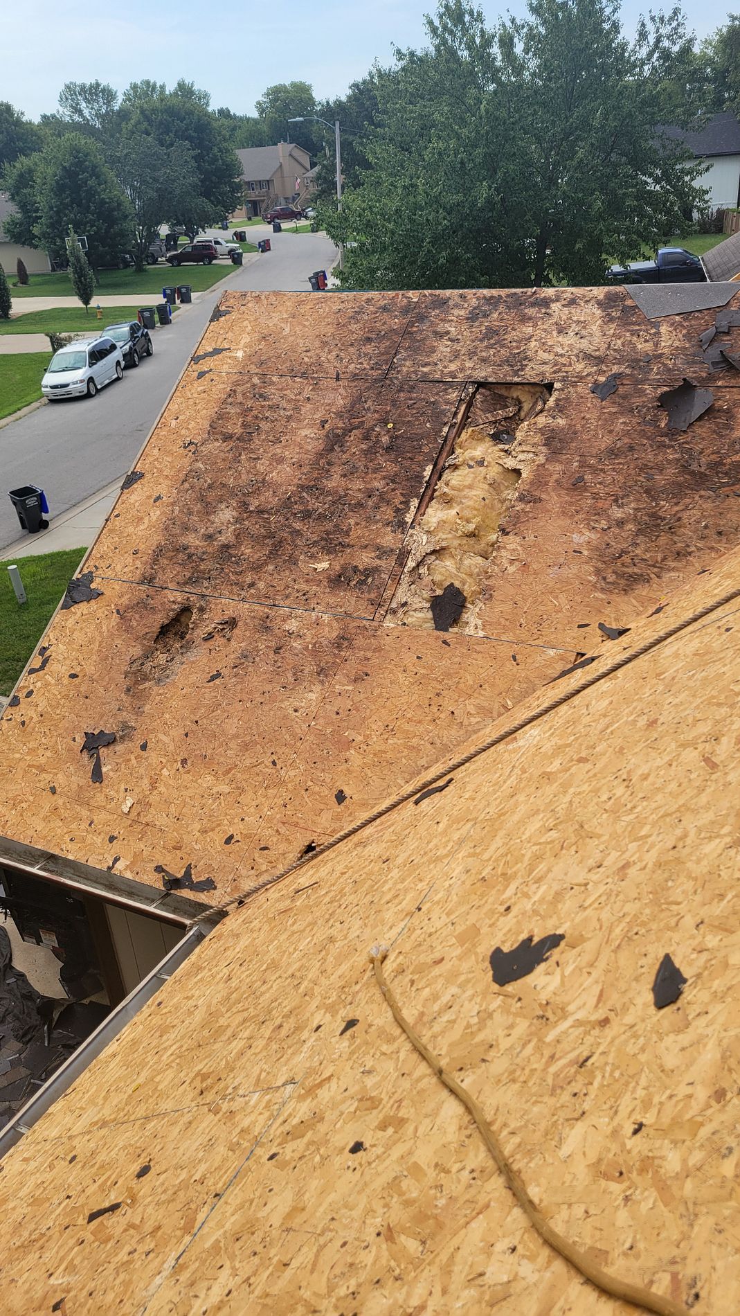 Damaged roof with large charred burn area overlooking a suburban street and trees
