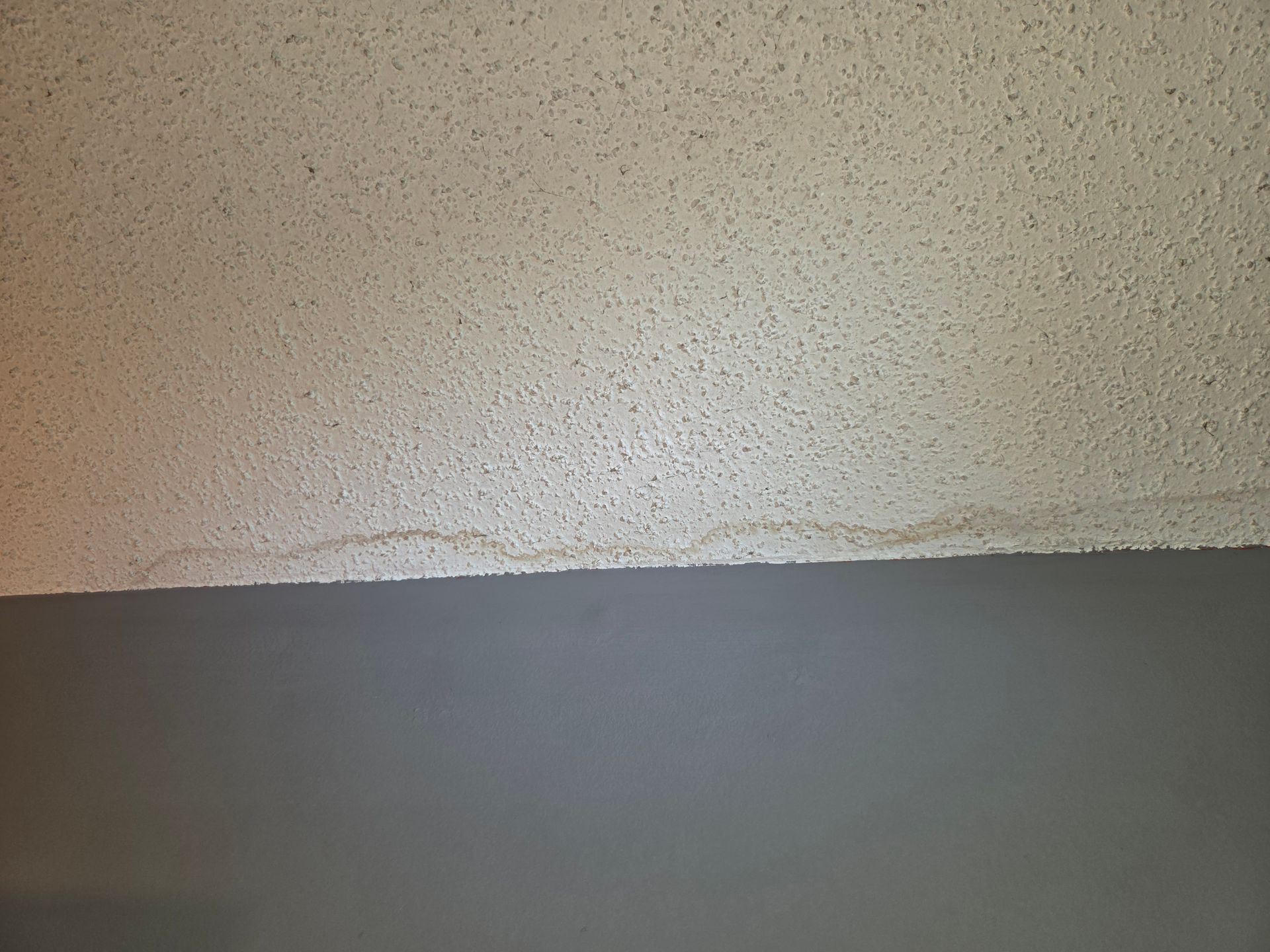 Close-up of a beige textured wall above a dark gray surface divider