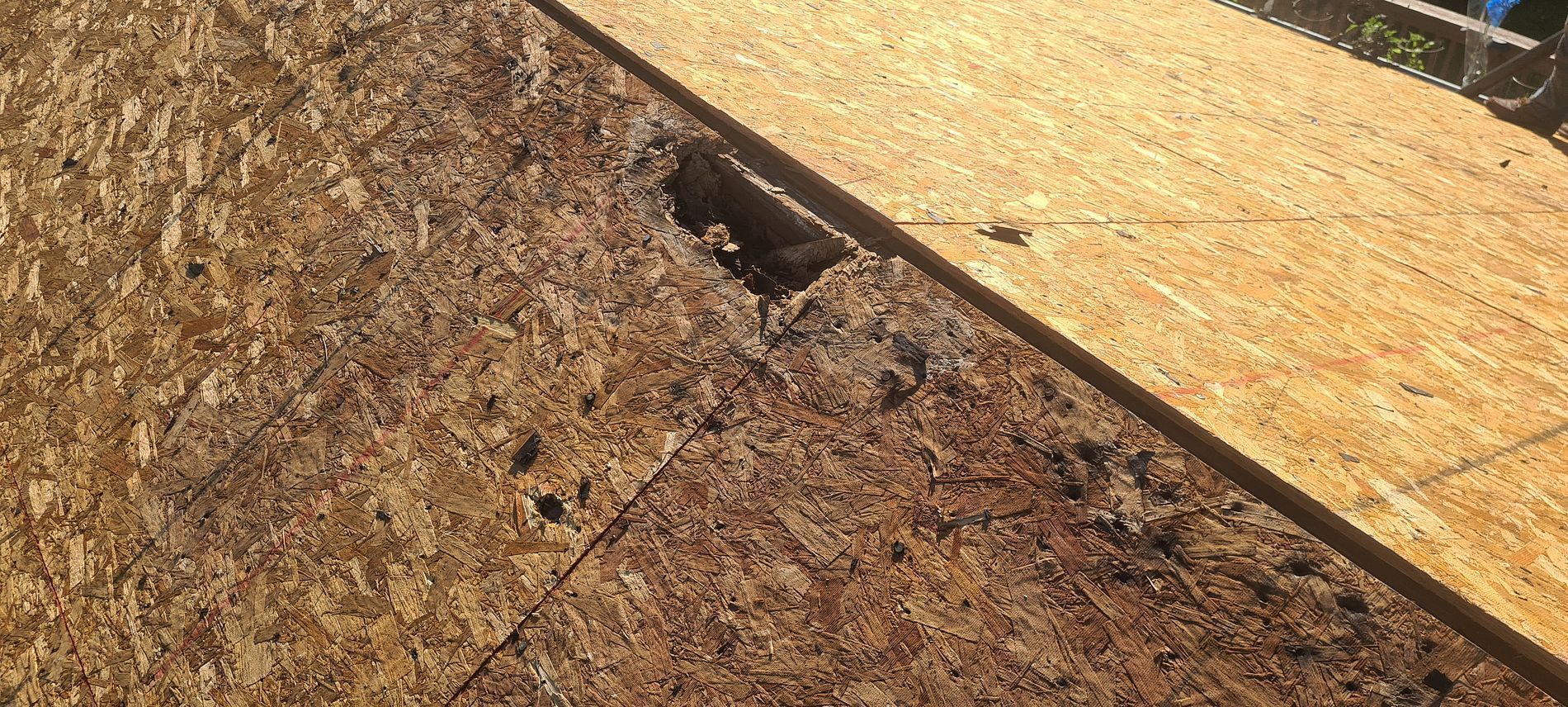 Close-up of damaged plywood roof with a large hole and exposed underlayment