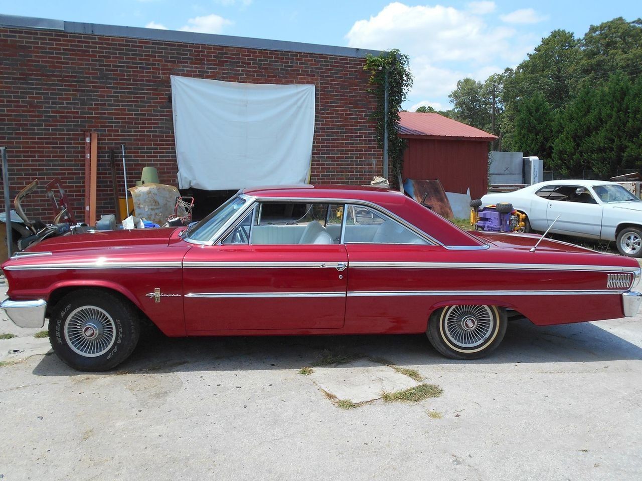 A red car is parked in front of a brick building