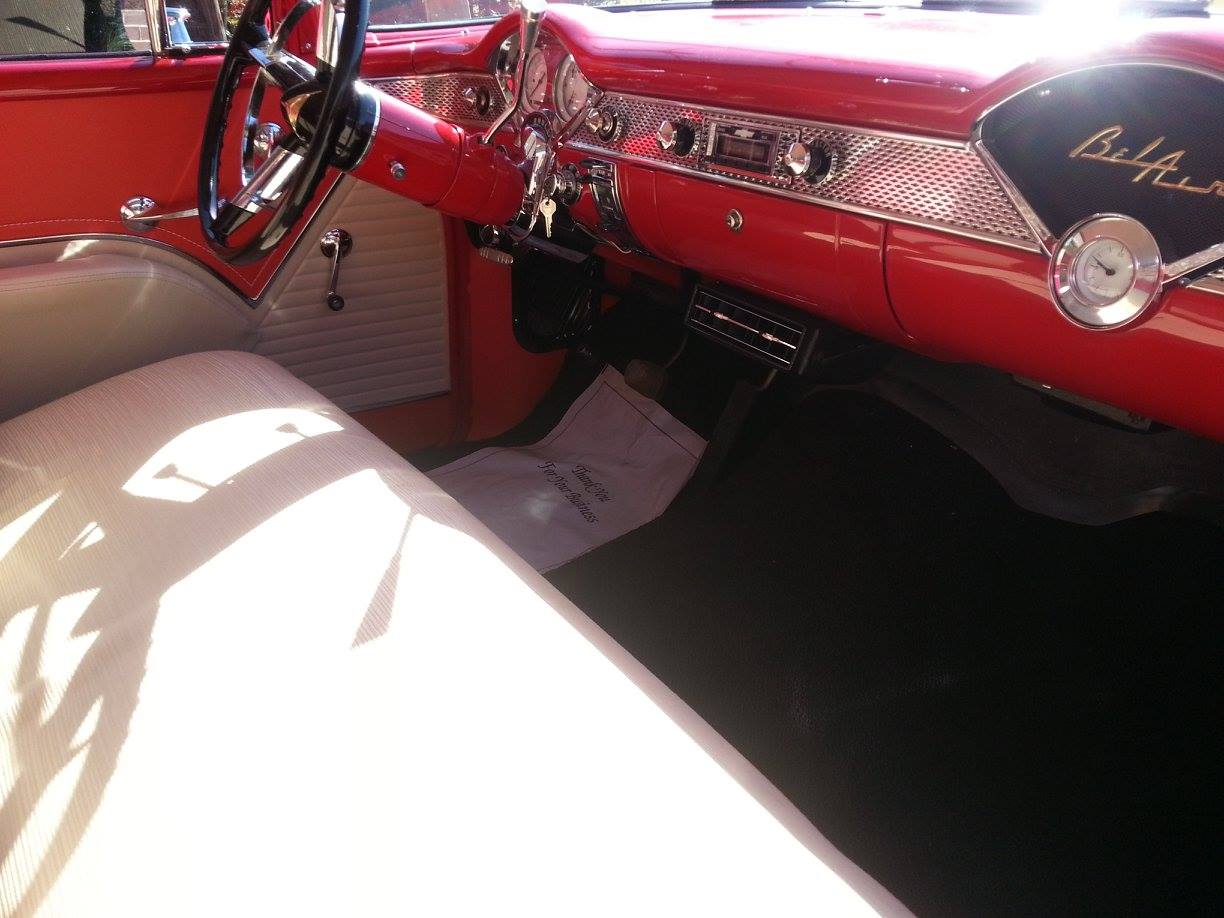 A red car with a fan on the dashboard