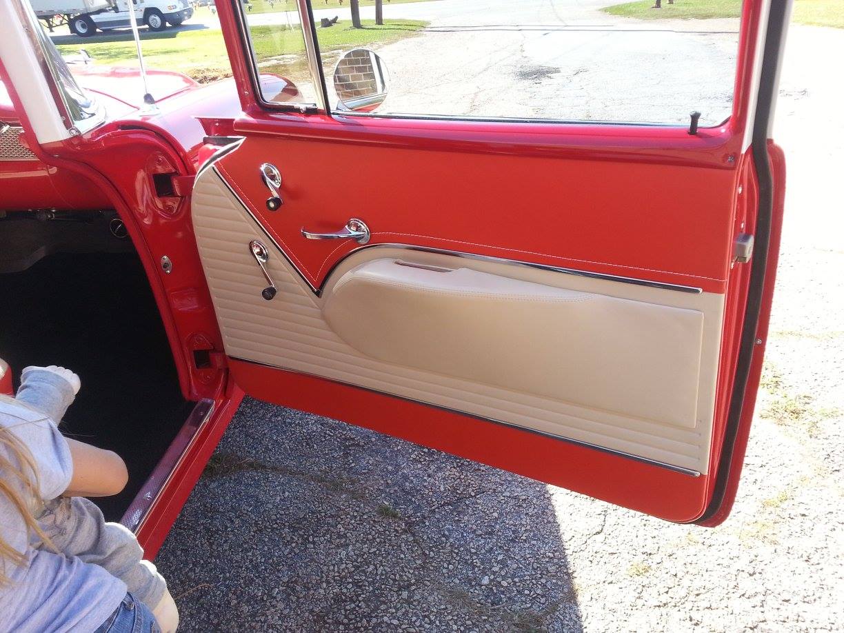 A child is sitting in a red car with the door open