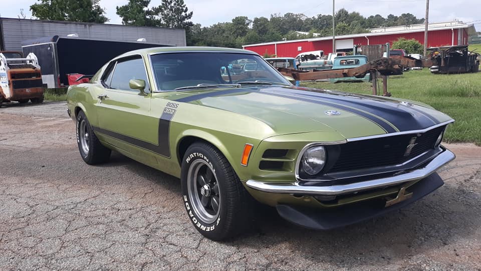 A green and black mustang is parked in a parking lot.