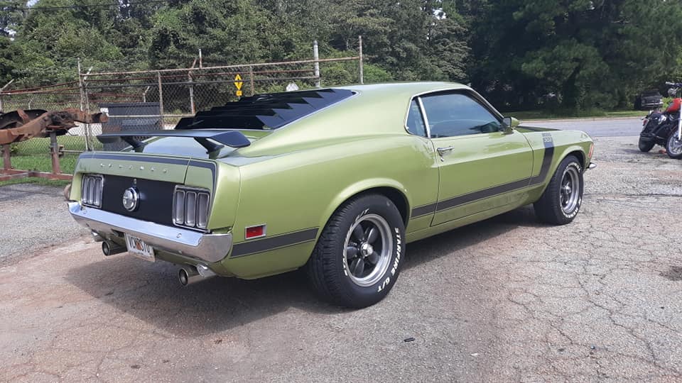 A green mustang is parked on the side of the road.