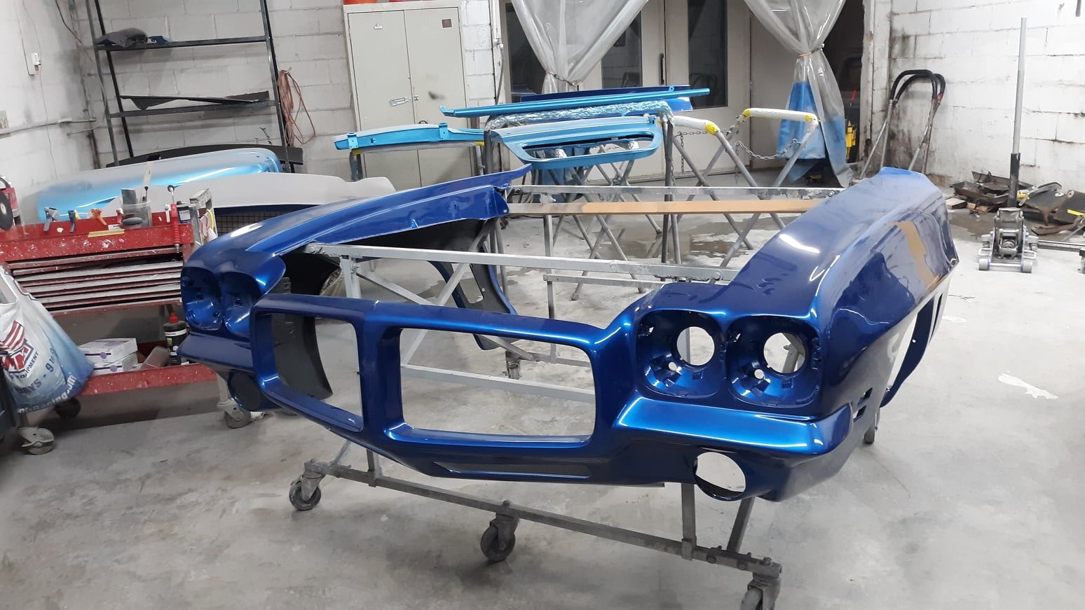 A blue car is sitting on a cart in a garage.