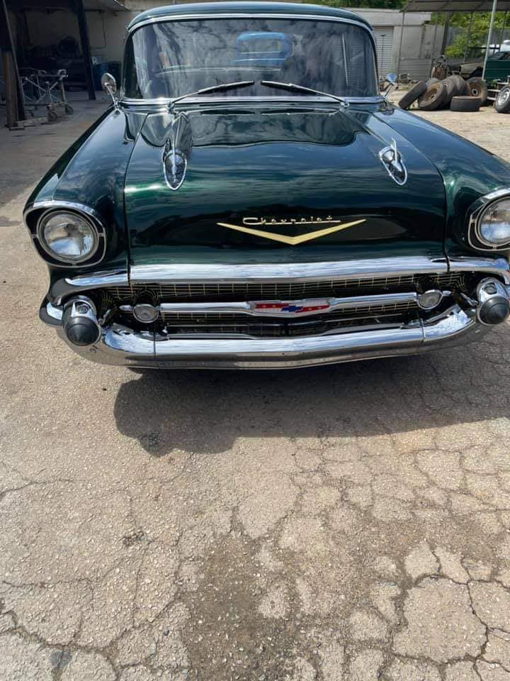 A green classic car is parked on the side of the road.