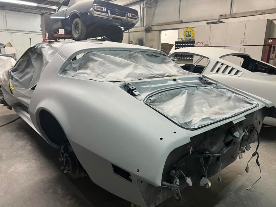 A white car is sitting in a garage with a blue car on top of it.