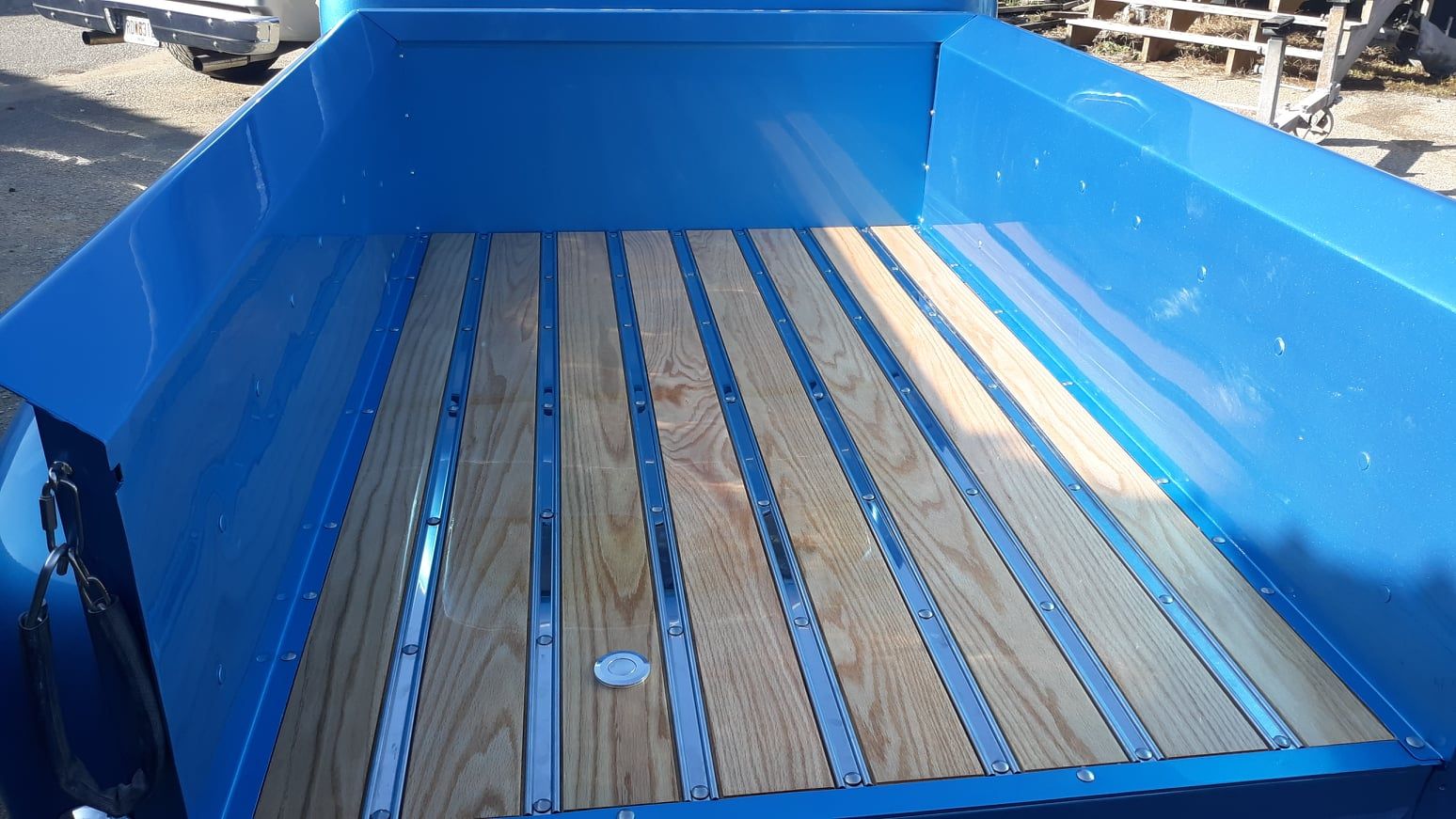 The back of a blue truck with a wooden bed