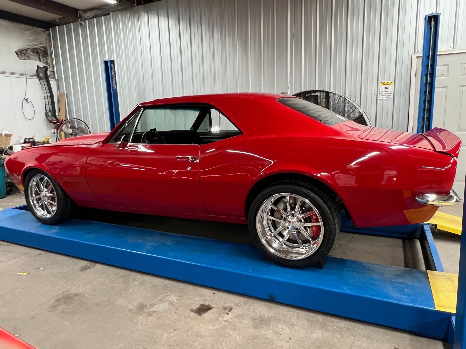 A red car is sitting on top of a blue lift in a garage.