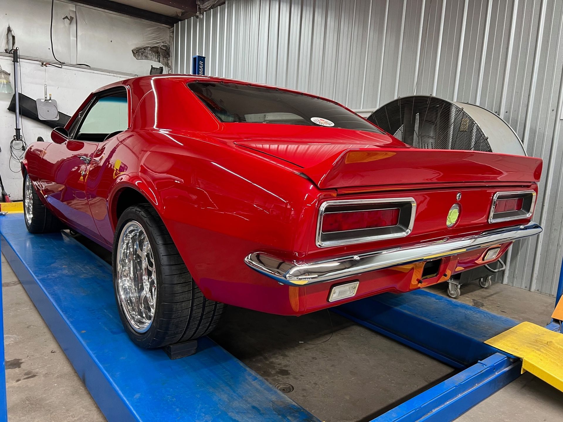 A red car is parked on a lift in a garage.