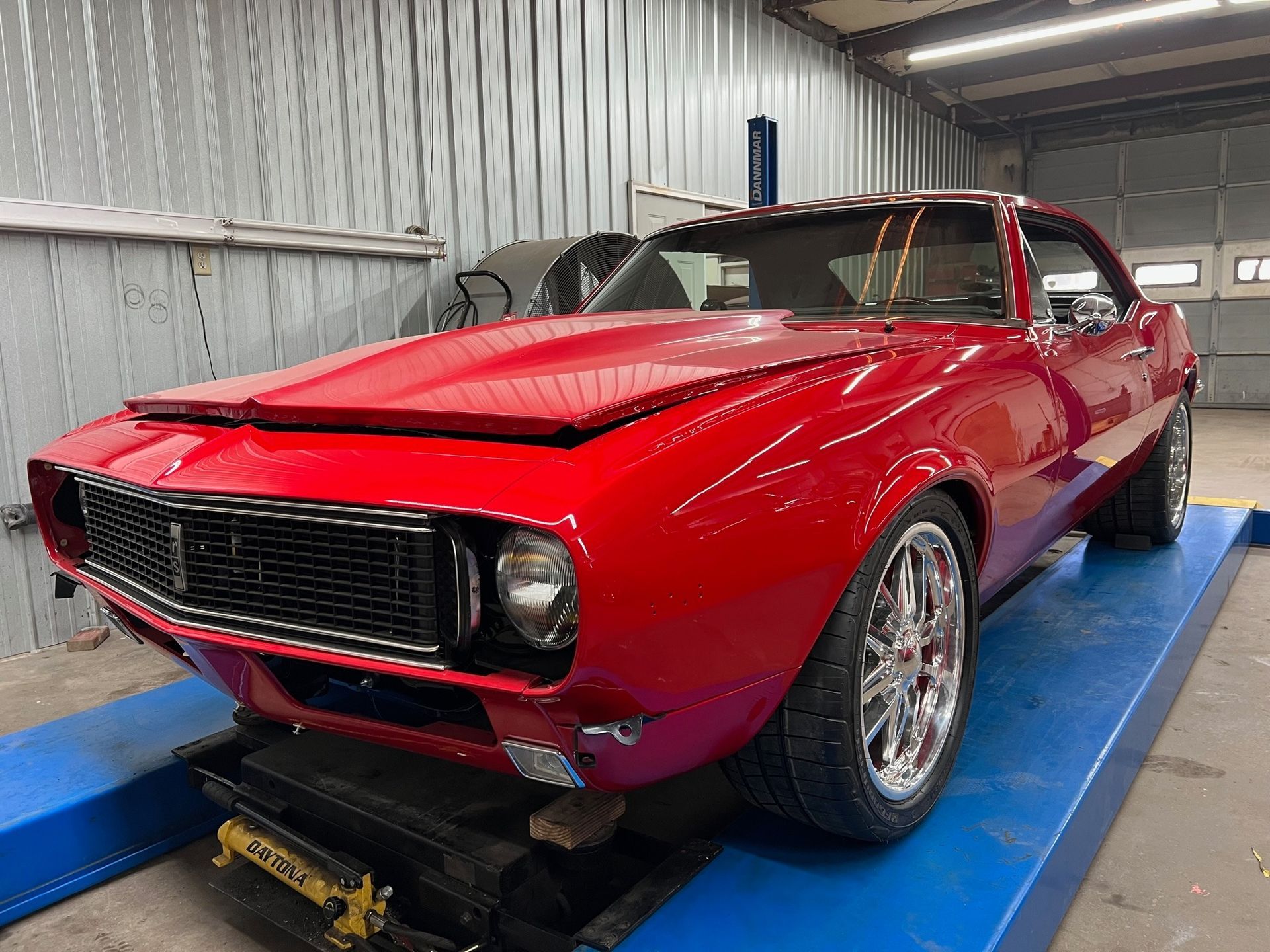 A red car is sitting on top of a blue ramp in a garage.
