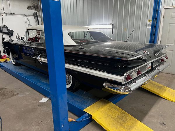 A black car is parked on a blue lift in a garage.