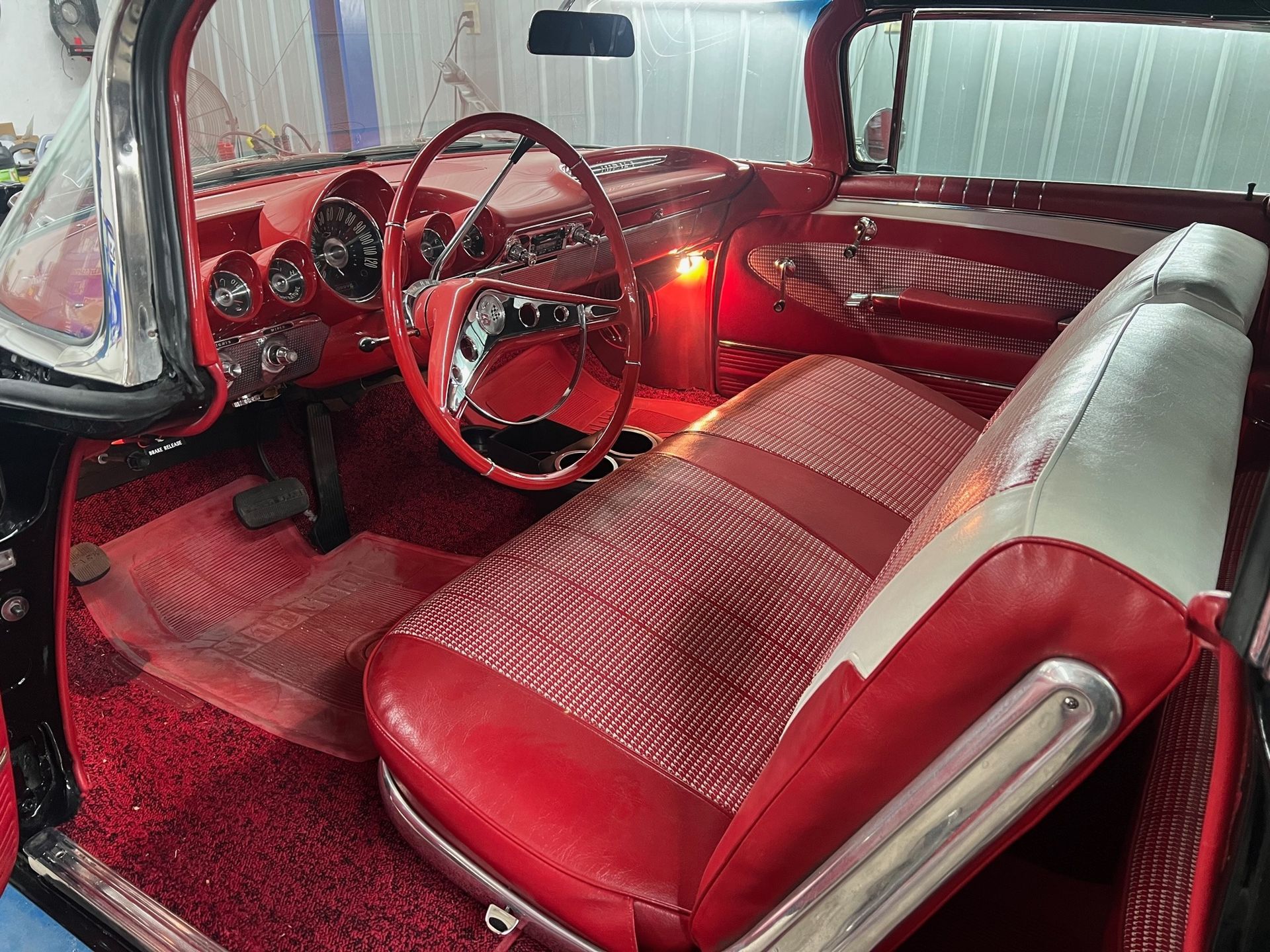 The interior of an old car with red seats and a steering wheel.