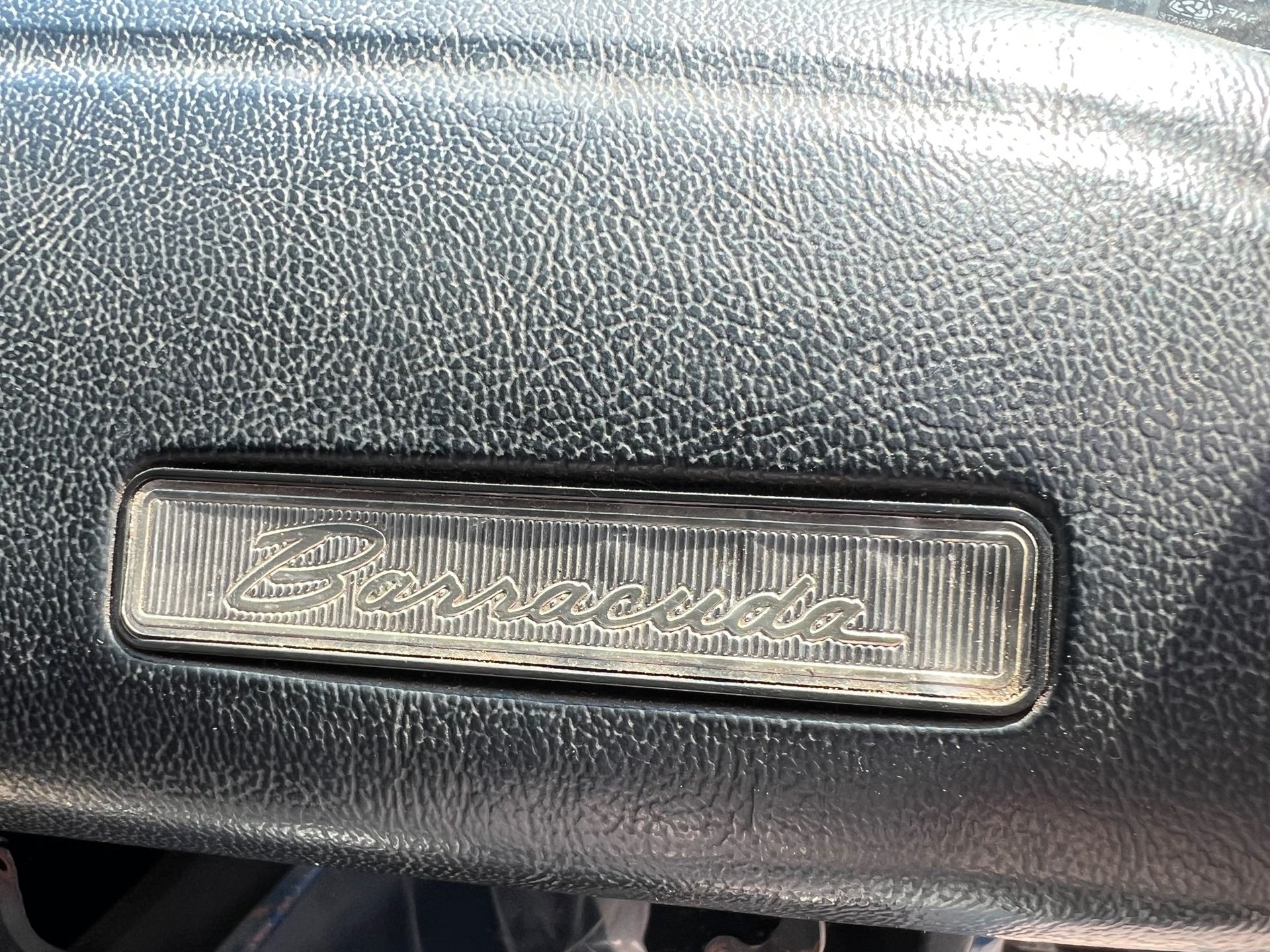 A close up of a 1973 Plymouth Barracuda car dashboard with a light on it.