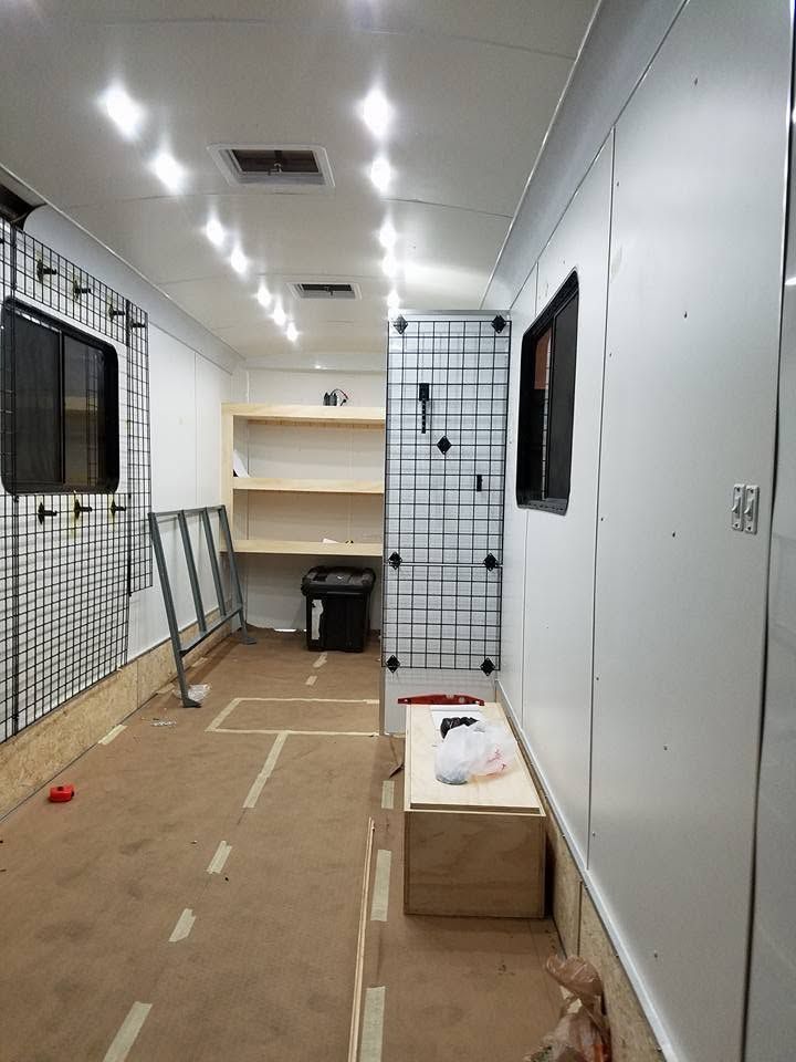 Narrow unfinished hallway with white walls, taped floor, and windows, resembling an under-construction room.