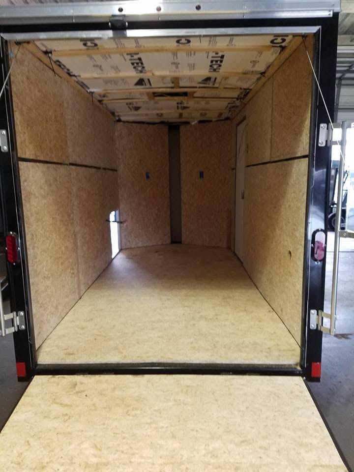 Empty cargo trailer interior with wood-paneled walls and open rear door