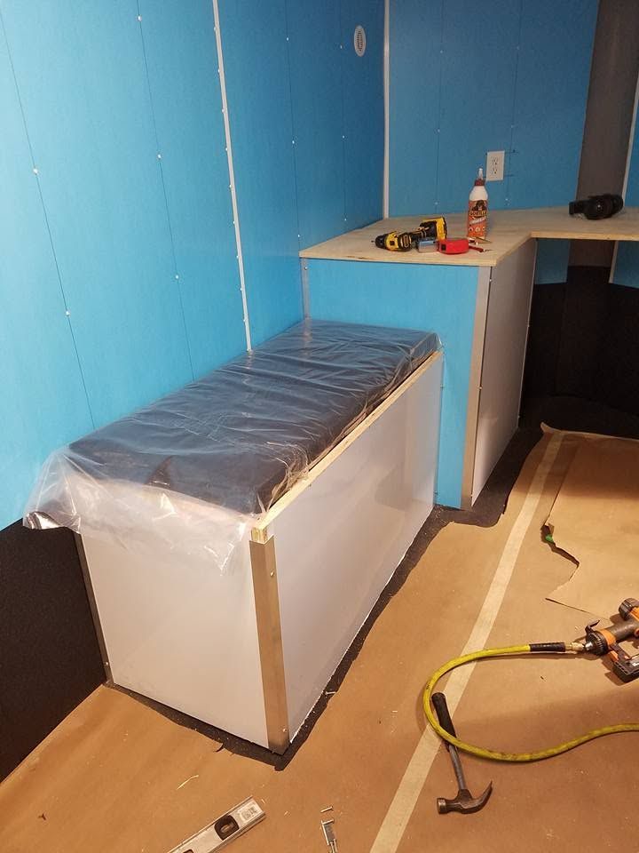 Small room with blue walls, a covered white cabinet, and tools on a workbench and floor.