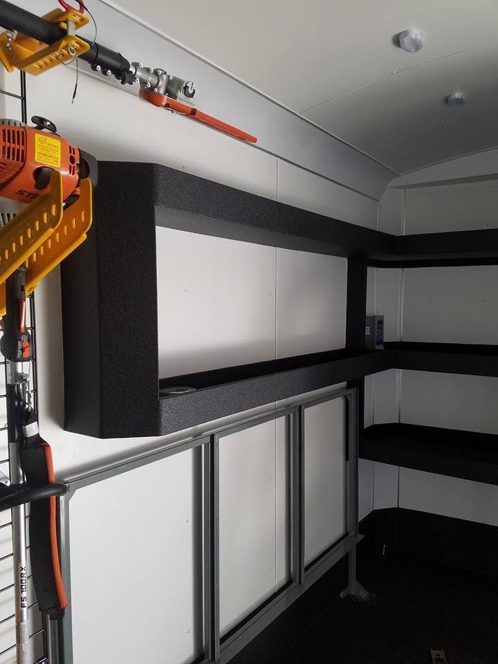 Interior of a custom van with white cabinets, black trim, and a long built-in shelf/storage area.