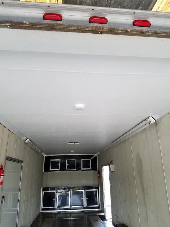 Empty cargo trailer interior with a closed rear door and red lights above the opening