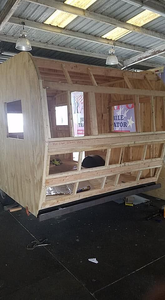 Wooden animal enclosure with small windows inside a warehouse-like space