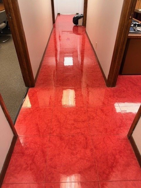 Glossy red hallway floor leading to a doorway, with walls on both sides and a small bag at the end.