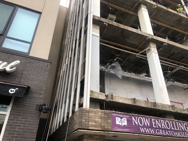 A building under construction with a sign that says now enrolling