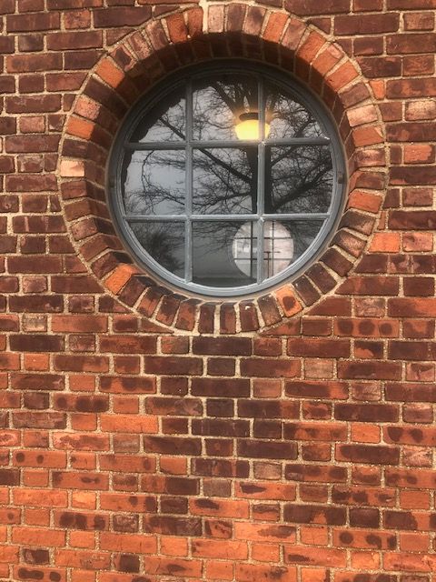 A brick wall with a round window in the middle